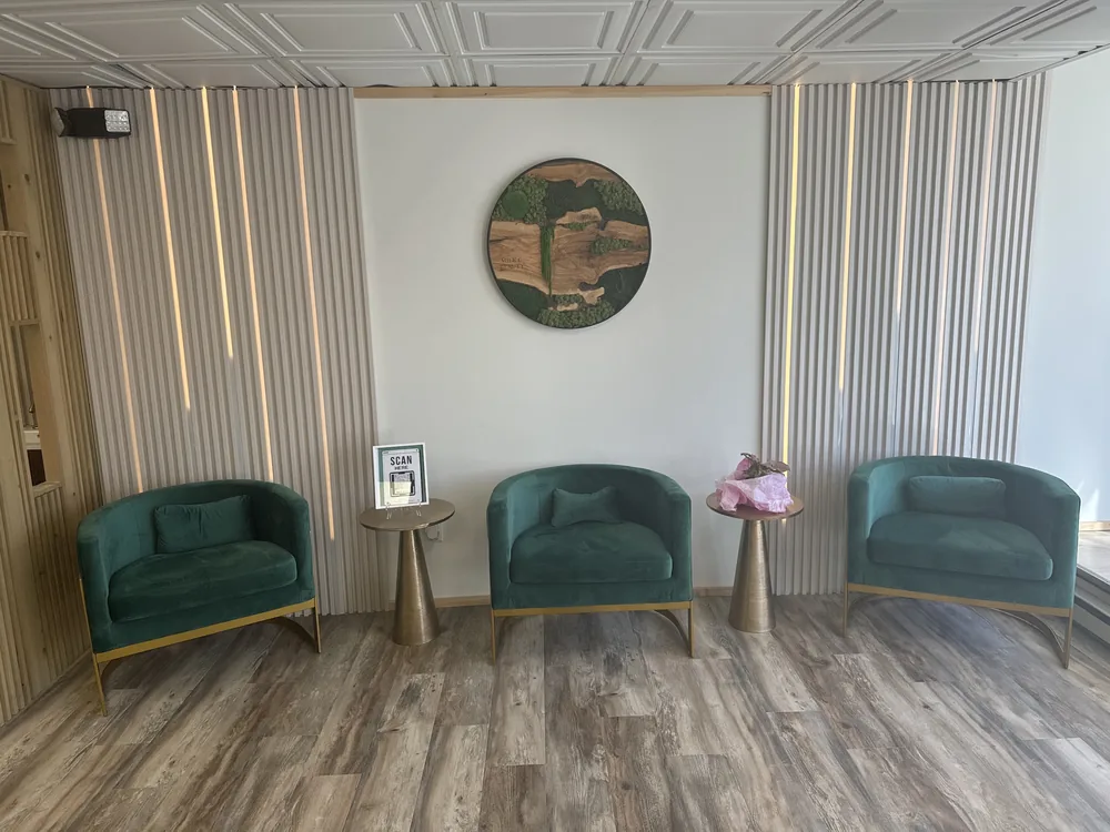 Mile C Beauty studio waiting area with green velvet armchairs and wood slat walls
