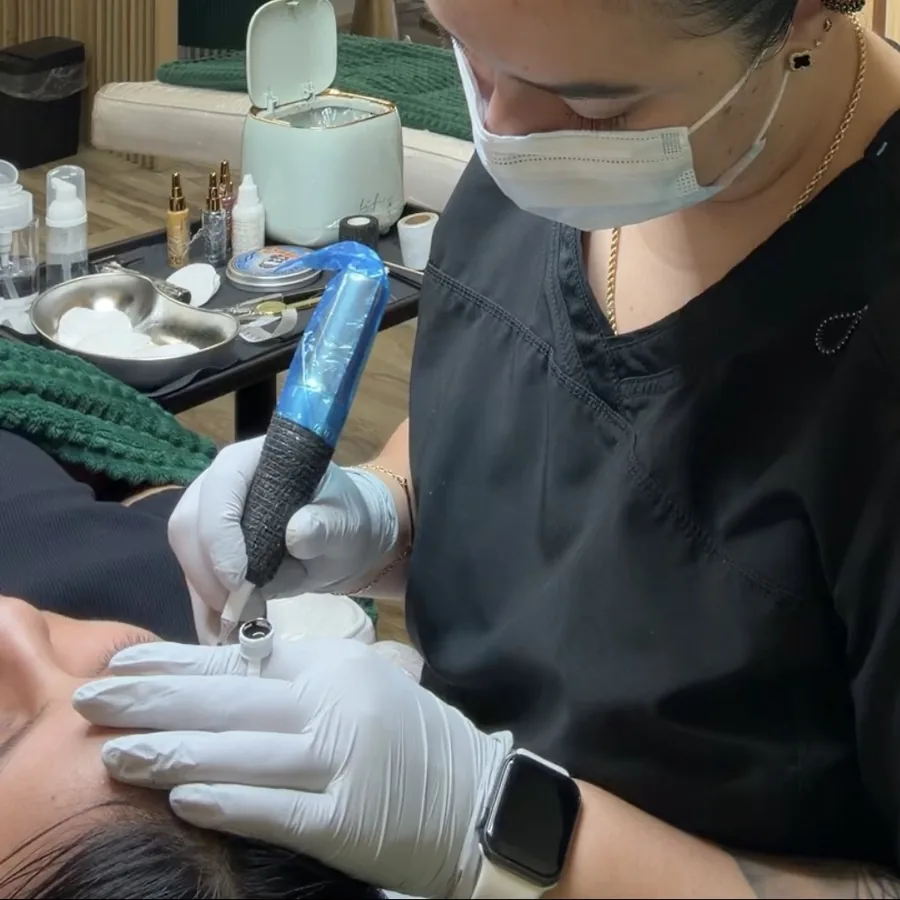 Ana Milena guiding the pigmentation pen over a client's brow in the Mile C Beauty studio